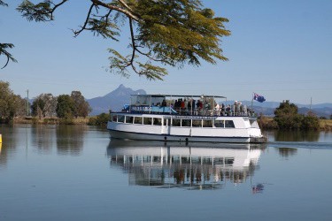 A river boat tour cruises the Tweed with Mt Warning in the background 